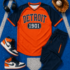 Baseball-themed outfit with orange and navy jersey, pants, shoes, and a baseball glove on a blue field background.