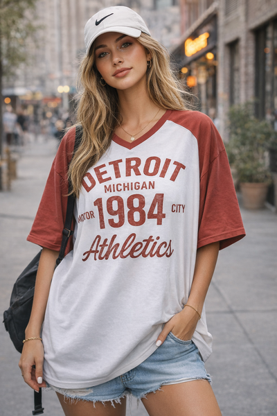 Woman wearing a 'Detroit Michigan 1984 City Athletics' t-shirt on a city street.