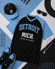 Black and blue t-shirt with 'Detroit Mich.' text, surrounded by a cap, sunglasses, necklace, and shoes on a geometric patterned background.