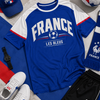 Blue and white sports jersey with 'France' and 'Les Bleus' text, surrounded by sports-themed items.