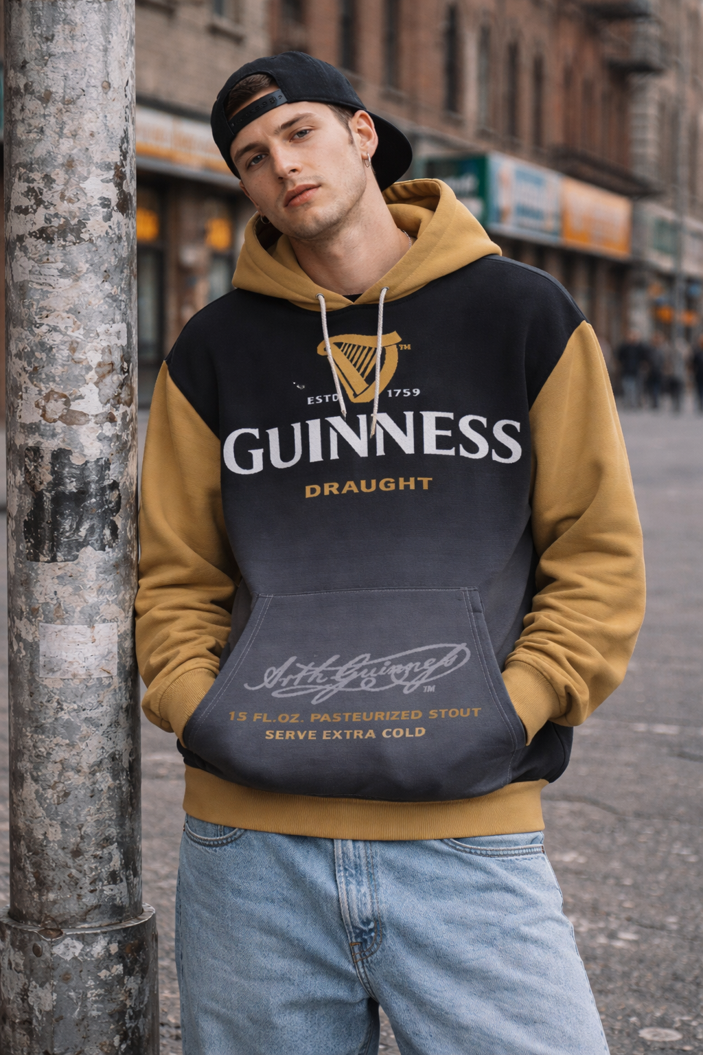 Person wearing a Guinness hoodie leaning against a street lamp.
