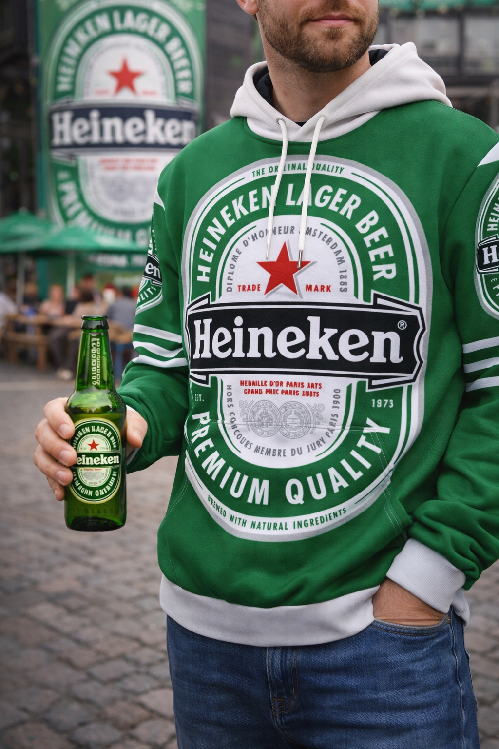 Person wearing a Heineken hoodie holding a bottle of Heineken beer.