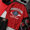 Red 'Houston' t-shirt with accessories on a gray surface