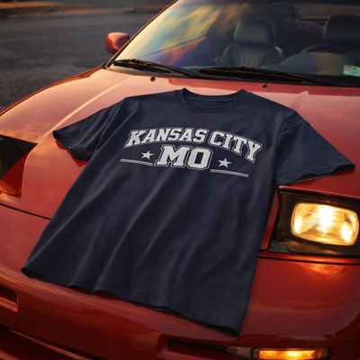 Navy blue t-shirt with 'Kansas City, MO' printed on it, draped over a red car.