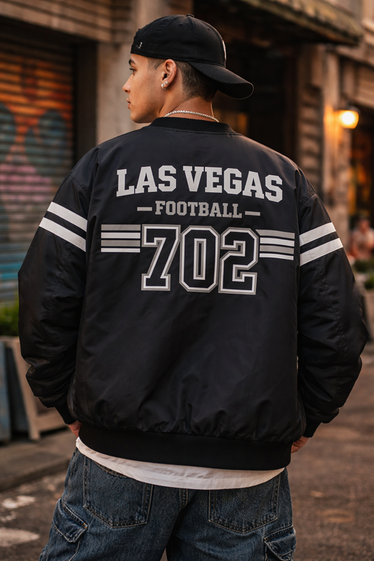 Person wearing a black jacket with 'Las Vegas Football 702' text outdoors.