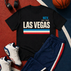 Black t-shirt with 'Las Vegas' text, blue tracksuit, white sneakers, basketball, and headphones on a sports court.