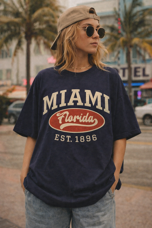 Person wearing a navy blue t-shirt with 'Miami, Florida' text in an urban setting with palm trees.