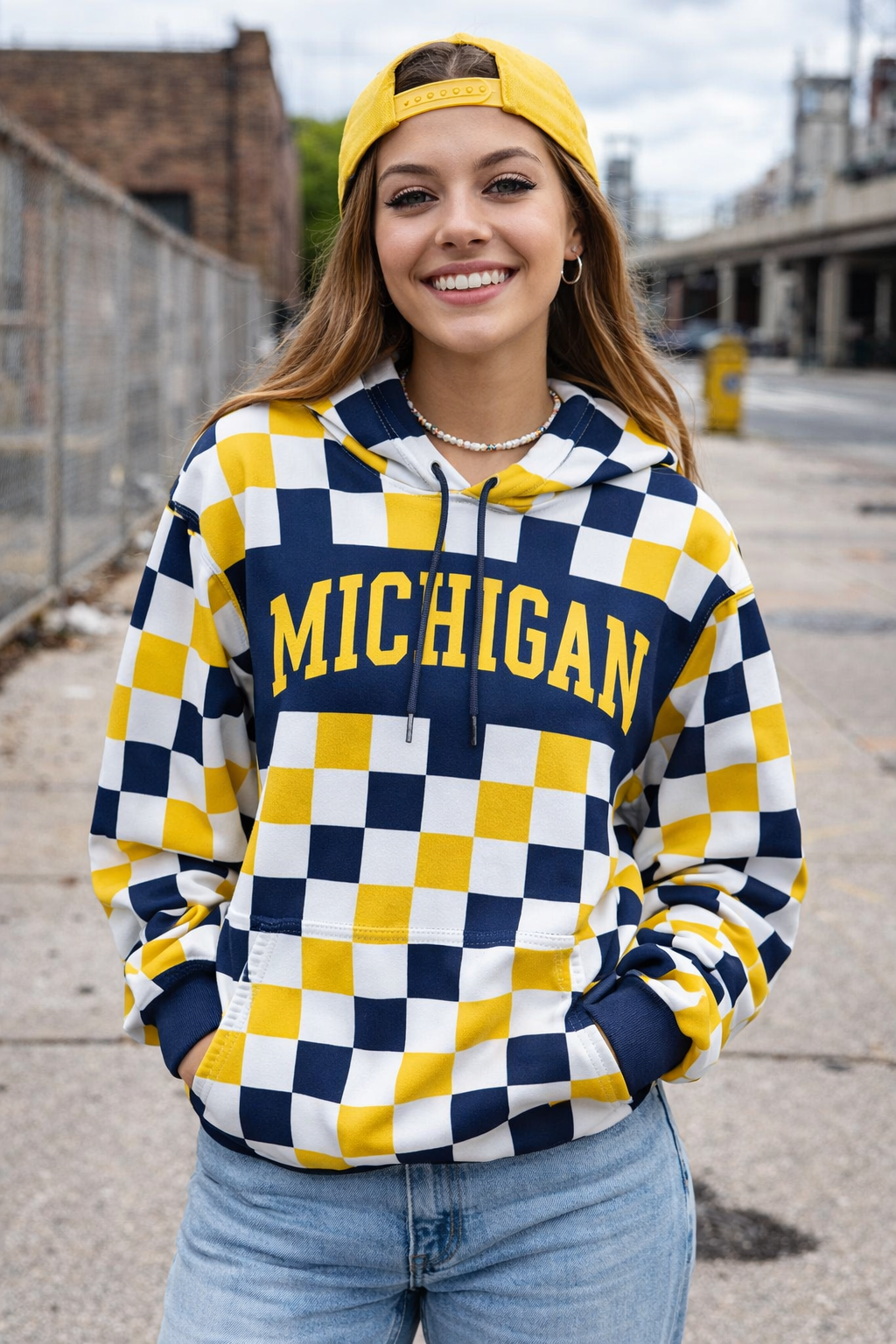 Person wearing a checkered 'Michigan' hoodie with a yellow cap outdoors.