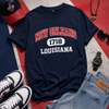 Navy blue t-shirt with 'New Orleans 1718 Louisiana' text, surrounded by casual items on a colorful background.