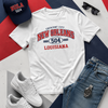 White t-shirt with 'New Orleans 504 Louisiana' design, navy cap, white sneakers, sunglasses, and blue jeans on a geometric background.