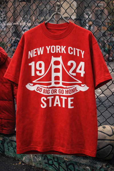 Red t-shirt with white text and graphics on a chain-link fence background