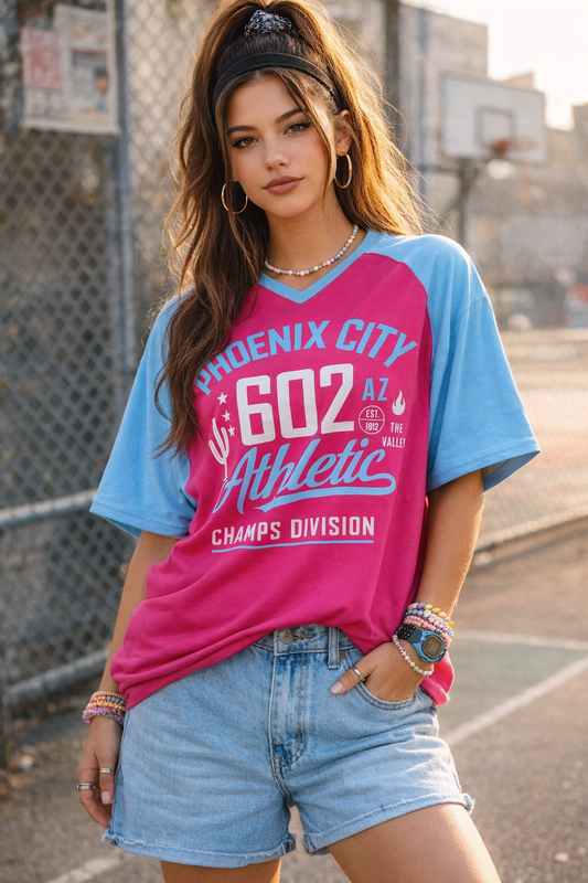 Woman wearing a colorful t-shirt with 'Phoenix City Athletic' design outdoors.