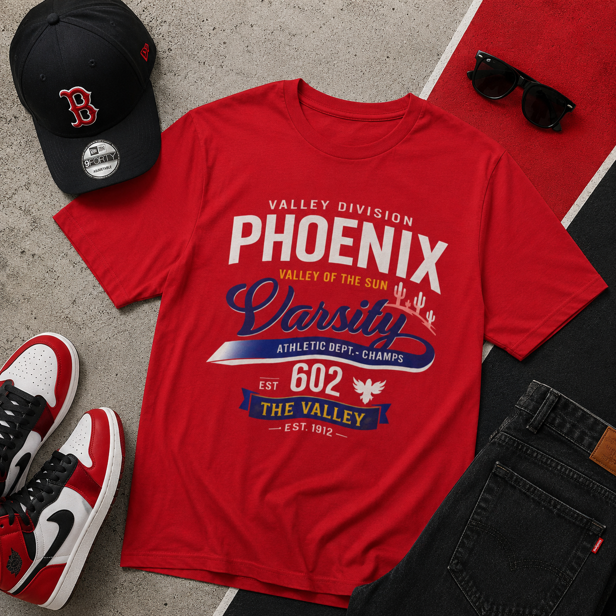 Red t-shirt with 'Phoenix' text, black cap, sunglasses, and sneakers on a concrete surface.