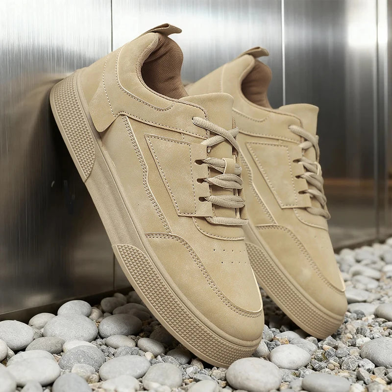 Beige sneakers on a bed of small stones with a metallic background