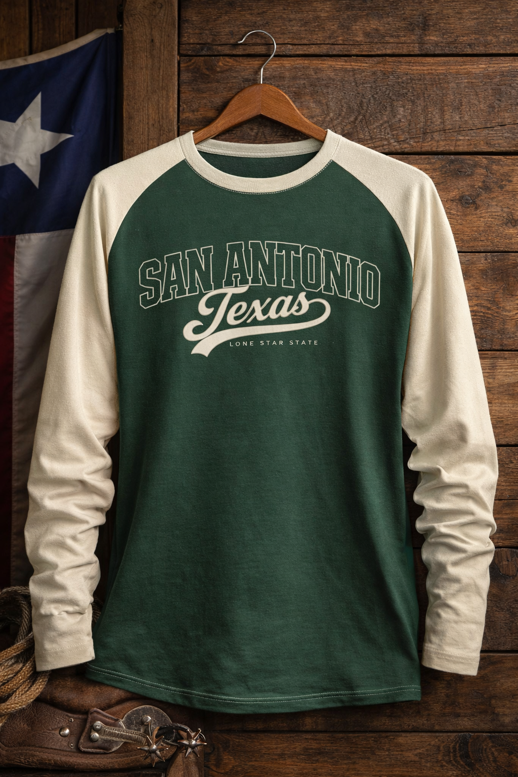 Green and white long-sleeve shirt with 'San Antonio Texas' text on a wooden hanger against a wooden wall.