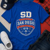 Blue t-shirt with 'San Diego' design, LA Dodgers cap, sunglasses, and white sneakers on a colorful background.