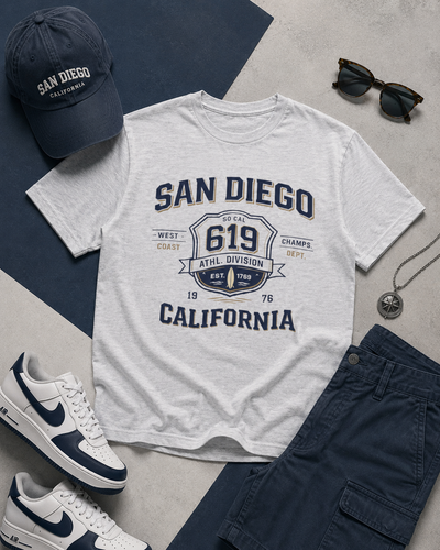 White t-shirt with 'San Diego, California' design, navy cap, sunglasses, and sneakers on a gray surface.