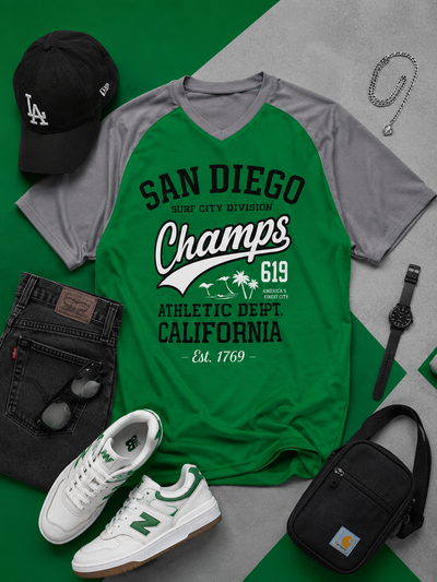 Green and gray t-shirt with 'San Diego Champs' text, black cap, white sneakers, black bag, and watch on a green and gray background.
