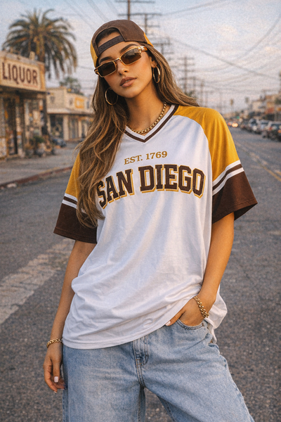 Woman wearing a 'San Diego' t-shirt on a street with palm trees and buildings in the background.