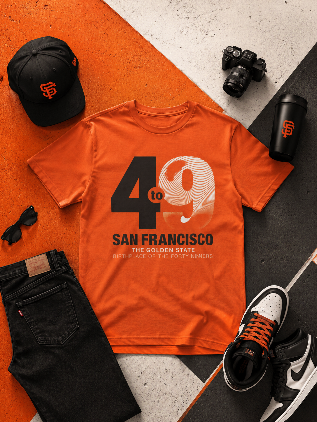 Orange t-shirt with 'San Francisco' design, black cap, camera, sunglasses, and shoes on a geometric patterned surface.