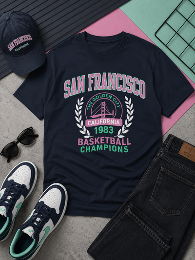 Navy blue t-shirt with 'San Francisco Basketball Champions' text, sunglasses, cap, and jeans on a textured surface.