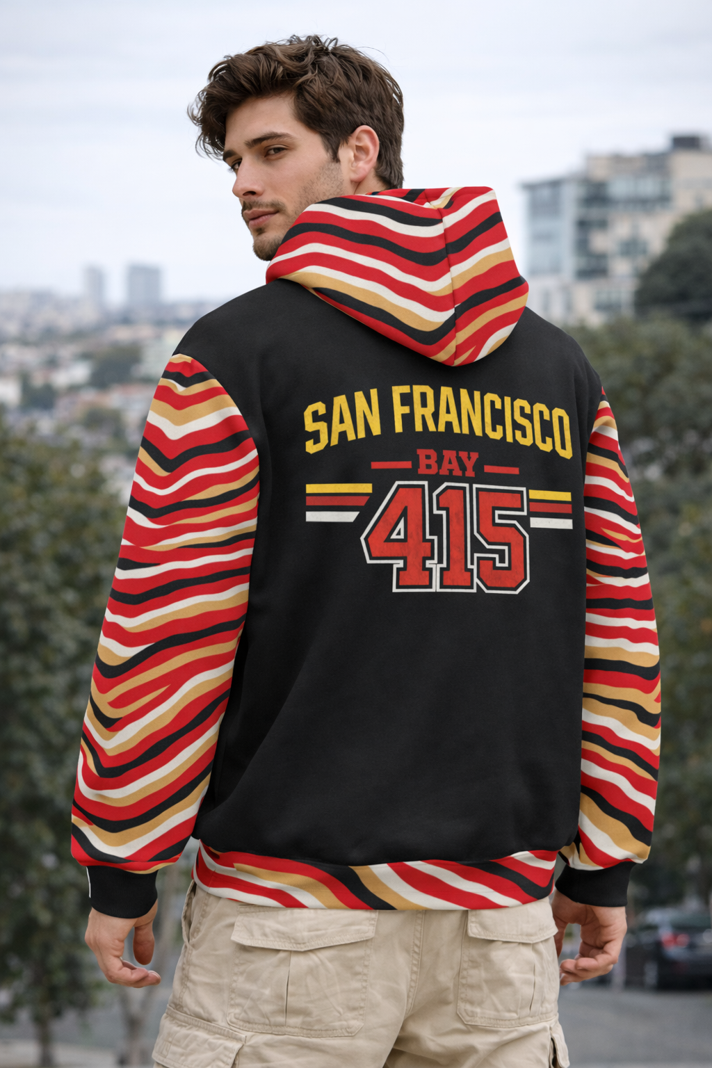 Person wearing a black hoodie with colorful sleeves and 'San Francisco Bay 415' text outdoors.
