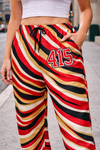 Person wearing colorful striped pants with number 415 on a city street.