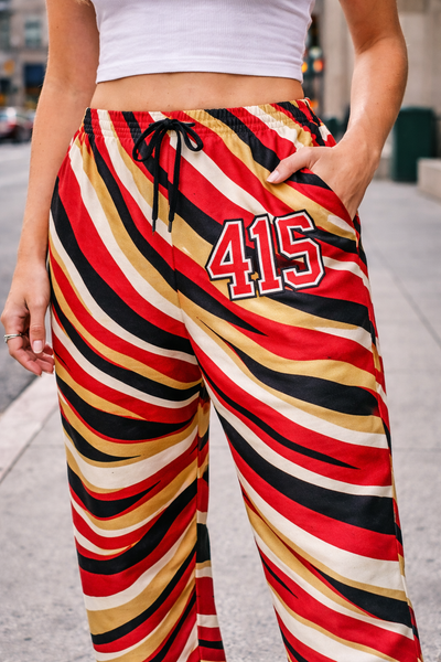 Person wearing colorful striped pants with number 415 on a city street.