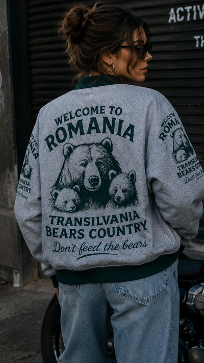 Person wearing a jacket with bear graphics and text, standing next to a motorcycle.