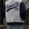 Person wearing a 'Kansas City MO' letterman jacket and cap outdoors.