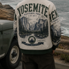 Person wearing a Yosemite National Park jacket standing by a car with ocean view