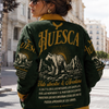 Woman wearing a green and yellow 'Huesca' sweater with bear graphics on a city street.